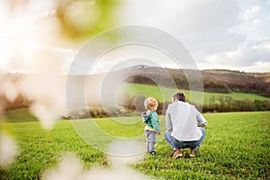 A father with his toddler son outside in spring nature.