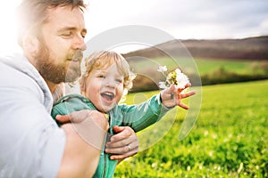 A father with his toddler son outside in spring nature.