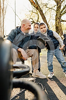 Father with his two sons on an outdoor sports ground in the park
