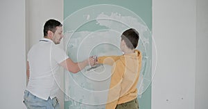 Father and his young son actively engaged in painting the walls of their new apartment. Moment during a renovation