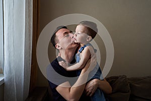 Father holding in arms his little son and kissing him outdoor. Happy family and father care concept.