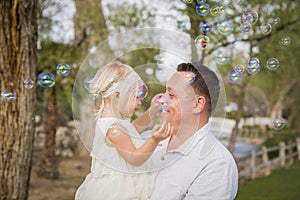 Father Holding Baby Girl Enjoying Bubbles Outside at Park