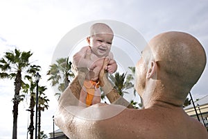 Father holding baby up high in sky