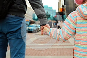 Father holding the daughter/ child hand behind the traffic lights.