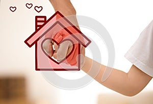 Father holding hands with child and illustration of house indoors. Adoption concept