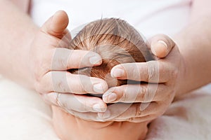 Father holding head of her newborn baby in hands.  Loving father hand holding cute sleeping newborn baby child. Beautiful