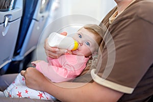 Father holding his baby daughter during flight on airplane going on vacations