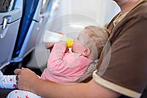 Father holding his baby daughter during flight on airplane going on vacations