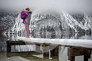 Father holding his baby daughter standing on a snowy pier