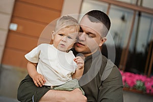Father holding his baby son tenderly in front of hotel window in the citty summer evening photo