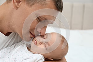 Father holding his cute sleeping baby at home, closeup