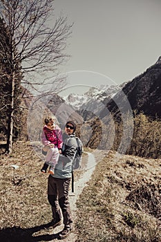 Father holding his daughter in embrace while walking on forest meadow.