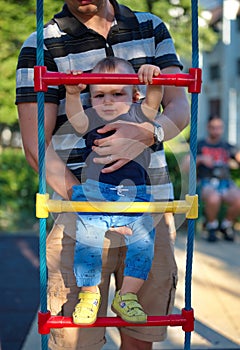 Father holding his little baby boy on playground