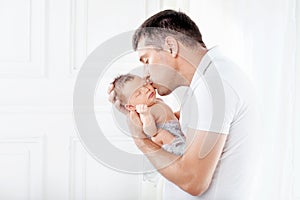 Father holding his newborn baby in  hands. Father kissing his baby