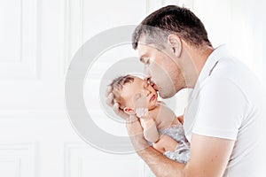 Father holding his newborn baby in  hands. Father kissing his baby