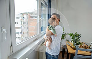 Father holding his newborn son, looking through window