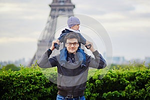 Father holding his son on shoulders near the Eiffel tower