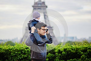 Father holding his son on shoulders near the Eiffel tower