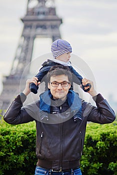 Father holding his son on shoulders near the Eiffel tower