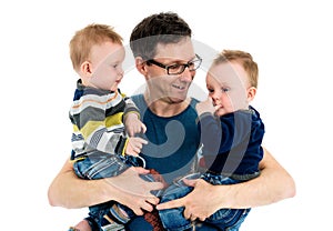 Father is holding his twin sons in his arms.