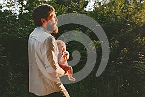 Father holding infant baby walking together in forest