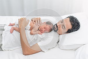 Father holding little one week baby sleeping on his chest. Tired dad sleeping with bagy boy