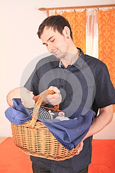 Father holding newborn baby boy lying in wicker basket