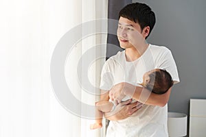 father holding newborn baby while looking out of window