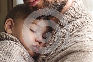 Father holding a small infant child sleeping in his arms