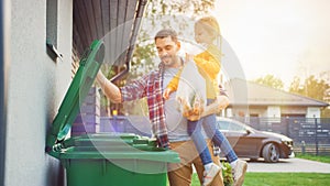 Father Holding a Young Girl and Throwing Away a Food Waste into the Trash. They Use Correct Garbage