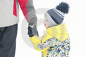 Father holds the boy`s hand in winter clothes, winter, family, hand in hand, lifestyle