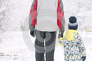 Father holds the boy`s hand in winter clothes, winter, family, hand in hand, lifestyle