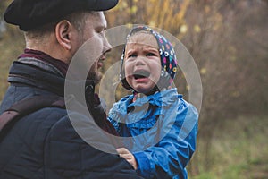Father holds daughter on hand while she is crying
