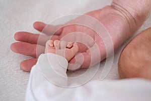 A father holds the hand of his newborn baby in his palm. Hands close up