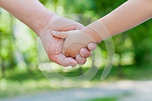 Father holds the hand of a little child in sunny park outdoor, united family concept