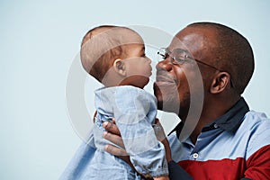 Father holds his little baby daughter in arms against pale blue background