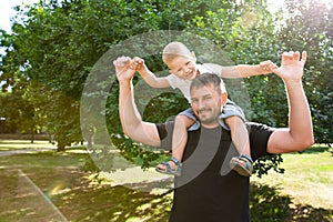 Father holds his son on his back like an airplane in park outdoor. Father plaing with son. Kindred love. Affection. Trusting photo