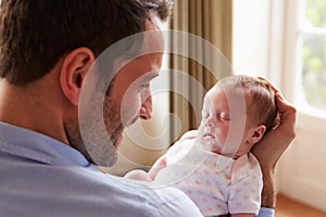 Father At Home With Sleeping Newborn Baby Daughter
