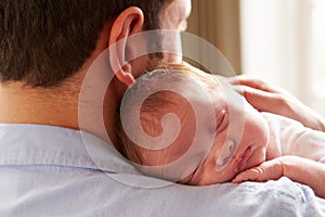 Father At Home With Sleeping Newborn Baby Daughter