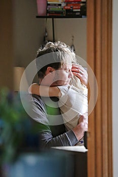 Father HUgging and Comforting Crying Child in Family Home