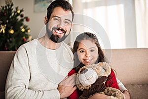 father hugging daughter with teddy bear and looking
