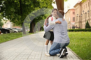 Father hugging his little daughter before school outdoors