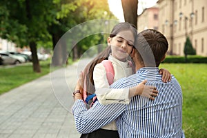 Father hugging his little daughter before school outdoors