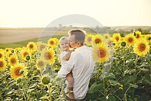 Father hugging his son while standing in the sunflowers field