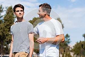 Father hugging and looking at teenager