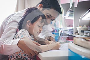 Father is hugging and teaching his daughter`s homework happily and full of smiles.Concept of Father`s Day