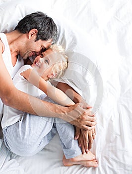 Father huggling her daughter on bed