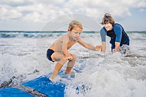 Father or instructor teaching his 4 year old son how to surf in