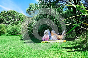 Father and kid lying on the grass in the shadow of the tree tops