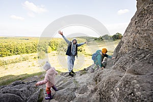 Father with kids climbing big stone in hill. Pidkamin, Ukraine